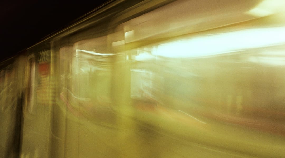 Motion-blurred shot of a subway train passing through a station, lit carriage windows streaking past