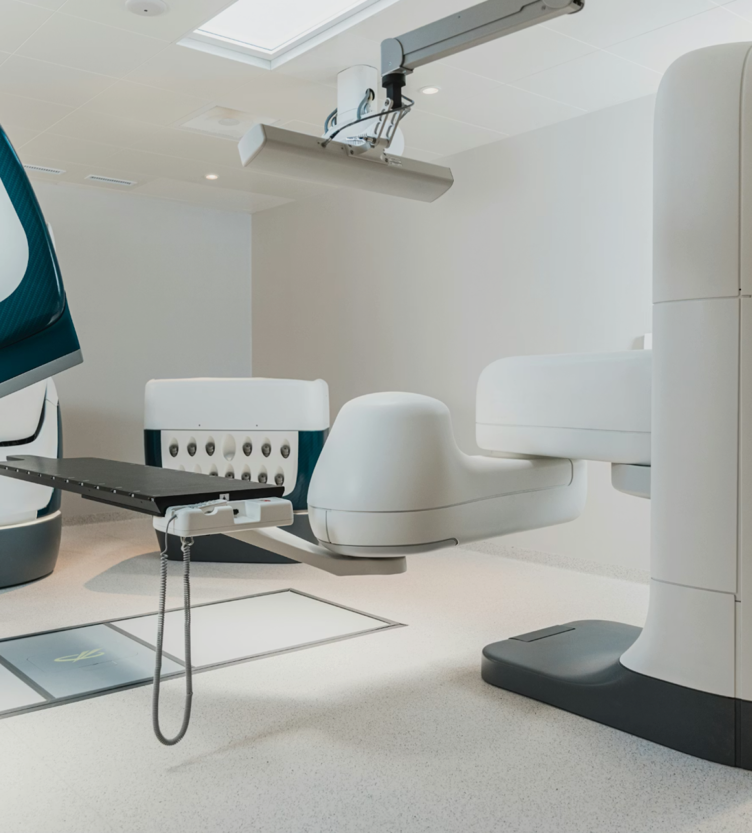 Modern medical imaging room featuring a large white and gray diagnostic machine with an attached black examination table.