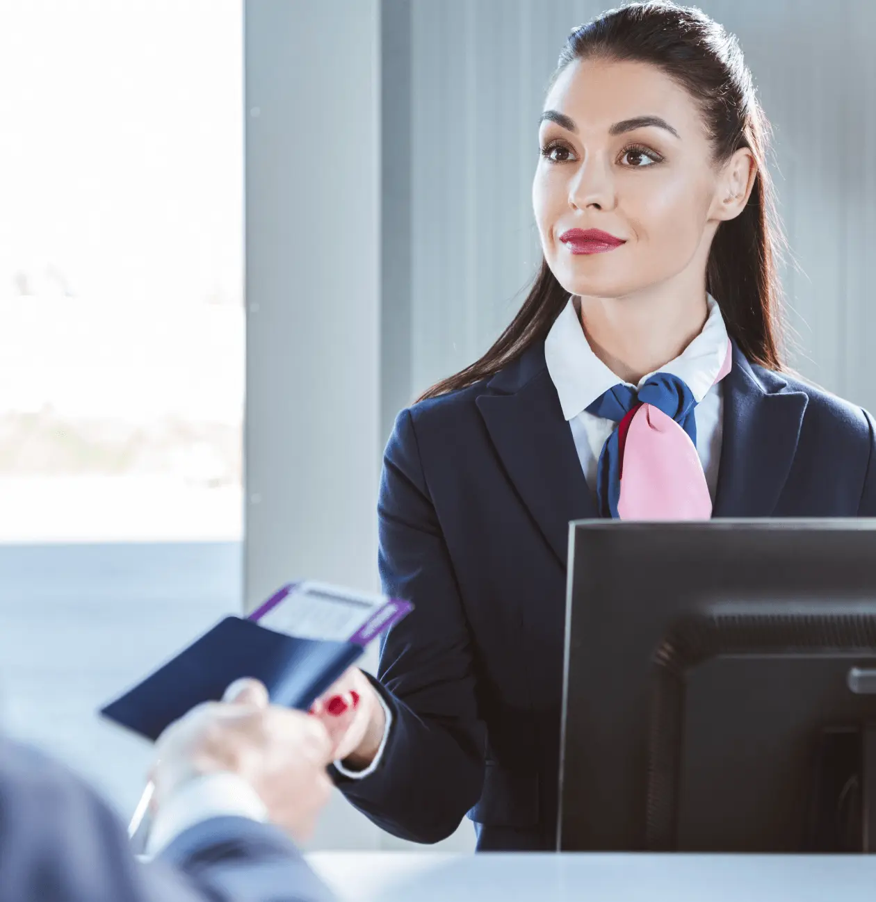 Agent d'aéroport professionnel en uniforme bleu recevant un passeport d'un voyageur à un comptoir.