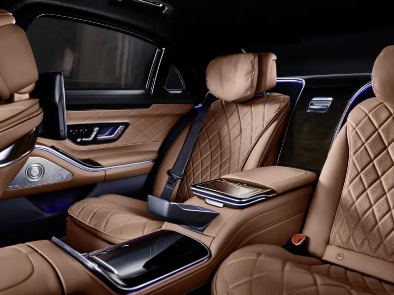 Intérieur luxueux arrière de voiture avec sièges en cuir marron matelassé et éclairage d'ambiance bleu.