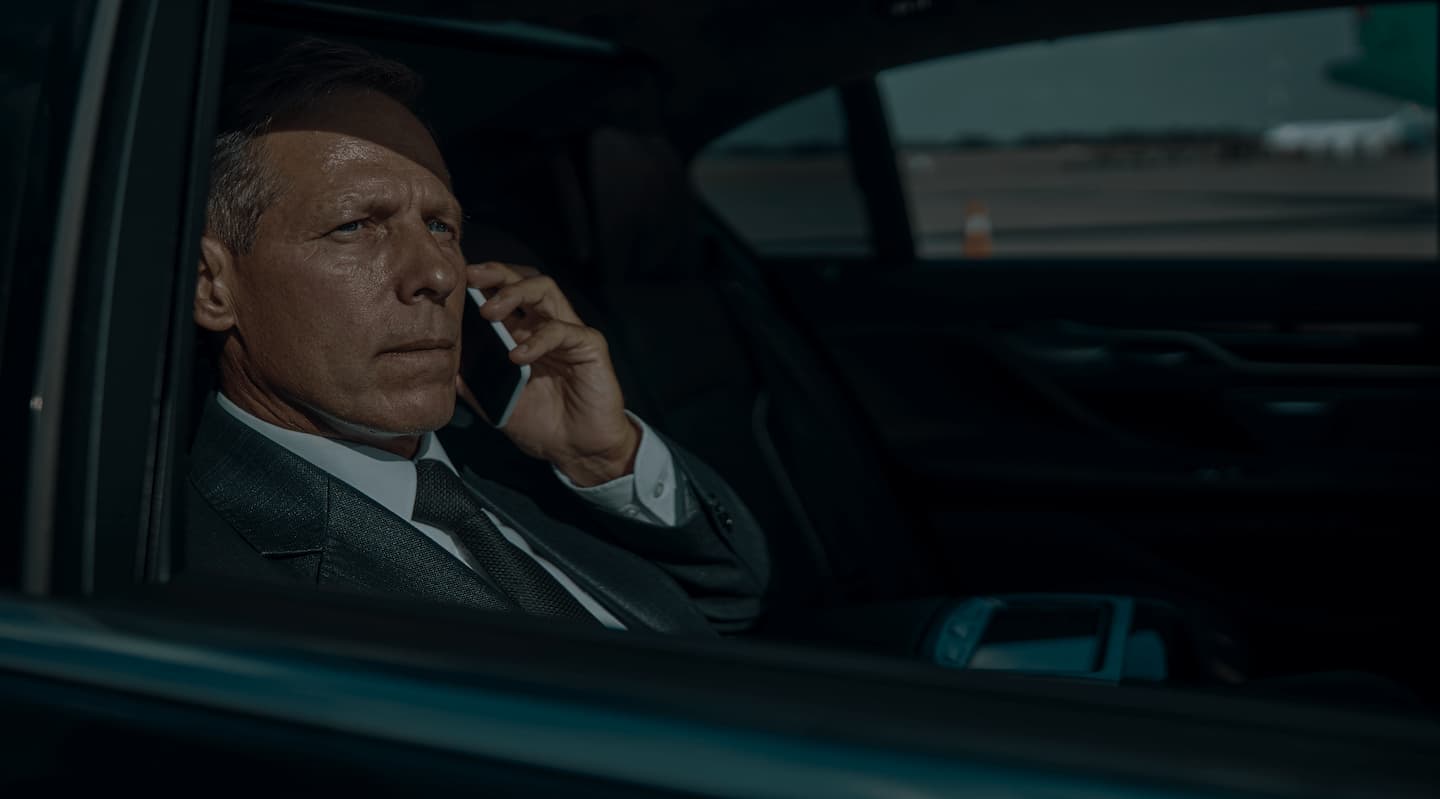 Homme d'affaires sérieux parlant au téléphone dans l'arrière d'une voiture.