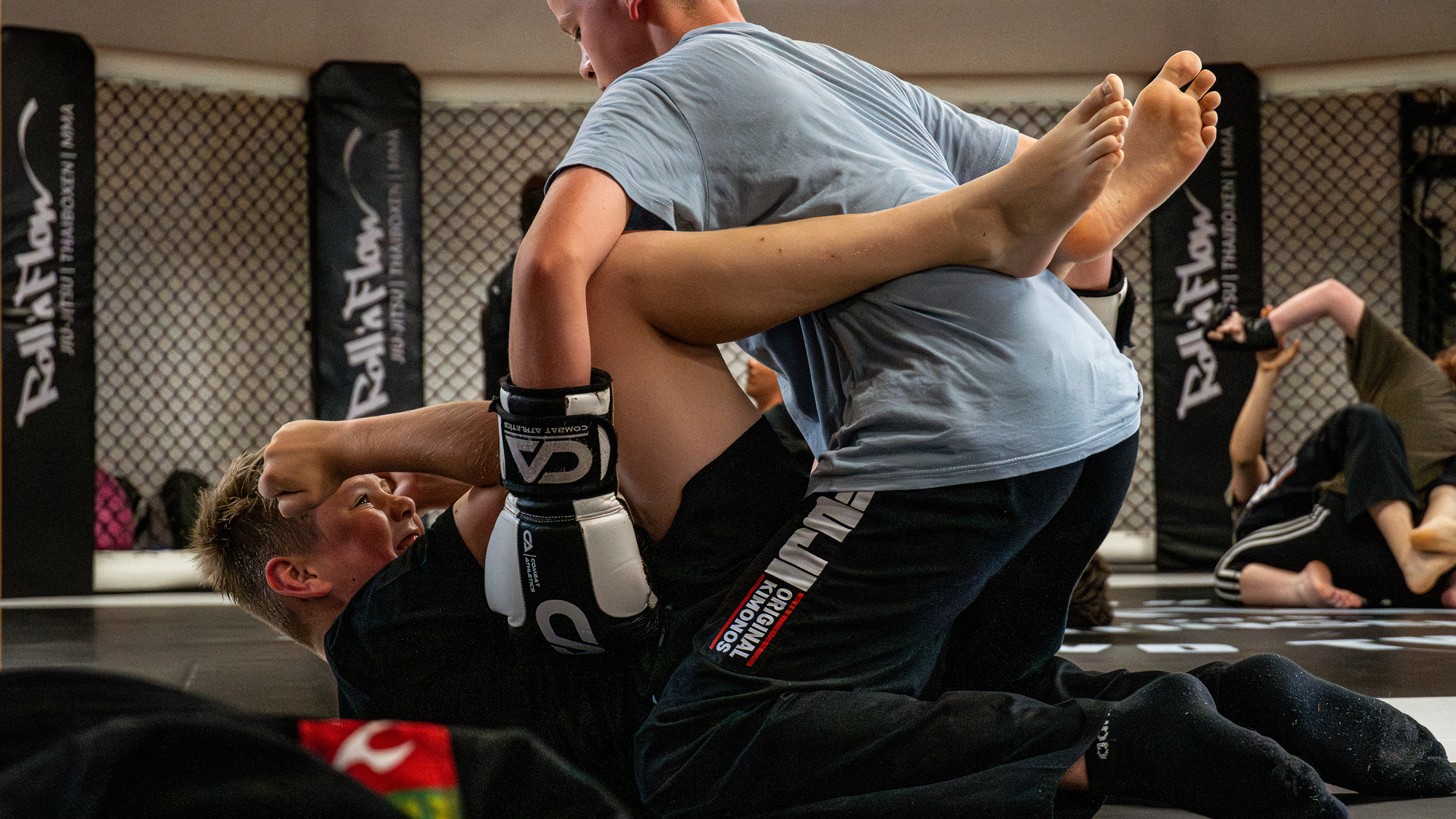 Zwei Jugendliche im Kampfsportunterricht kämpfen mit Boxhandschuhen im kontrollierten Sparring.