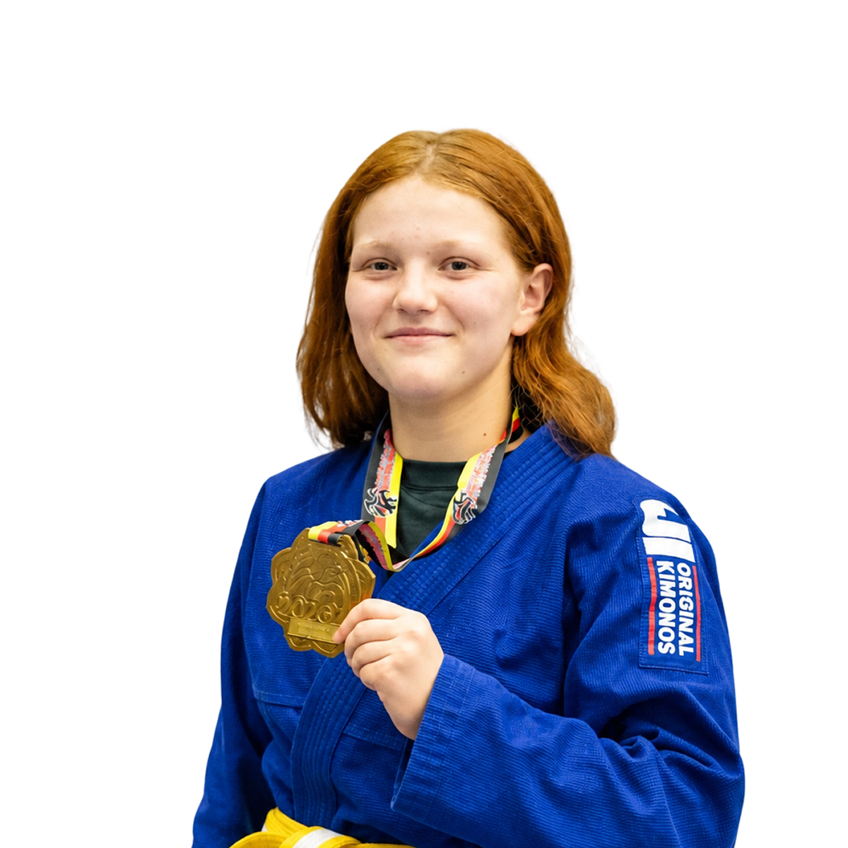 Jugendtrainerin Sarah hält goldene Medaille in blauem BJJ-Anzug.