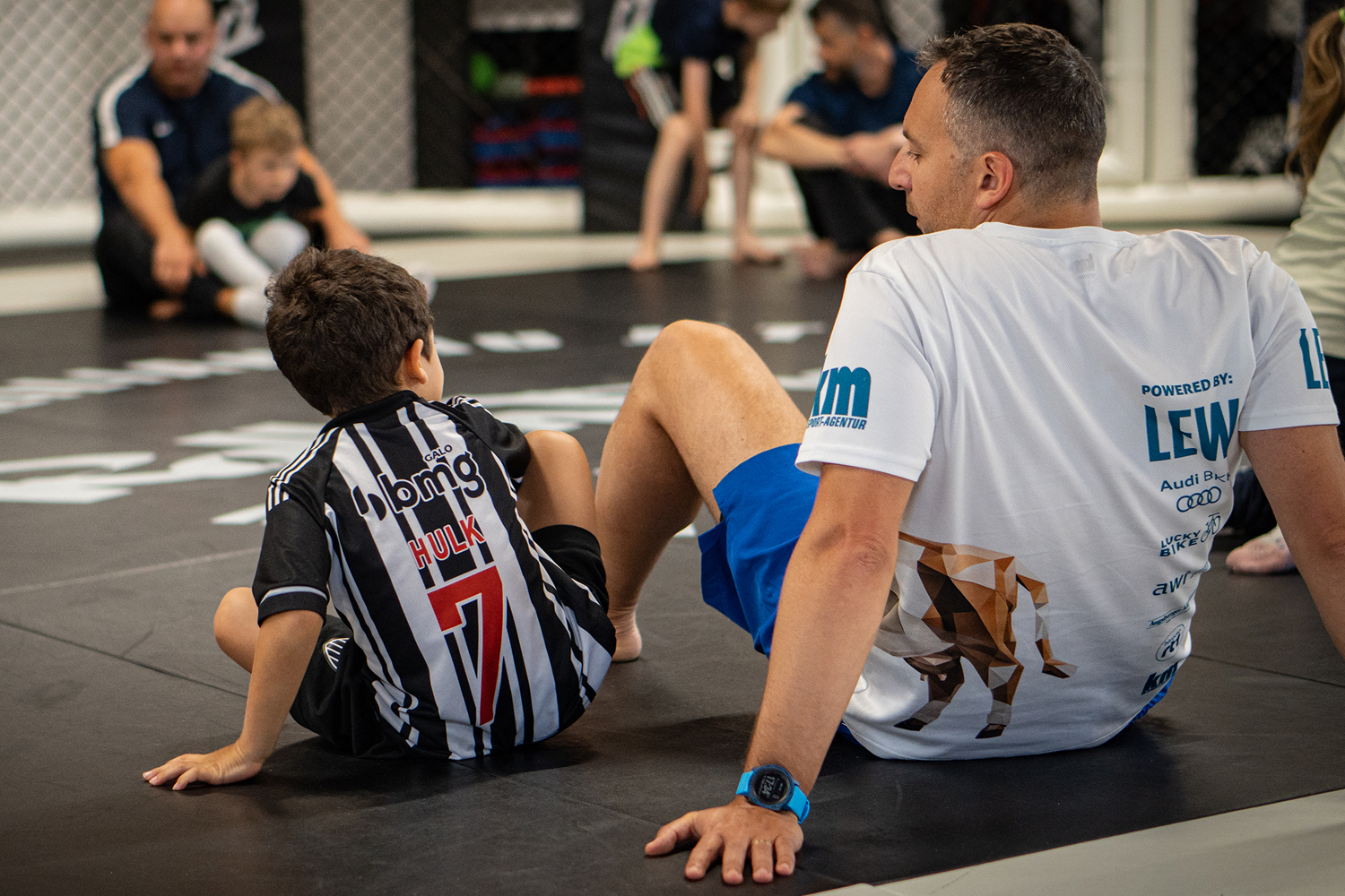 Zwei Jungen trainieren Jiu Jitsu Techniken auf der Matte, einer hält den Arm des anderen in einer Armbar.