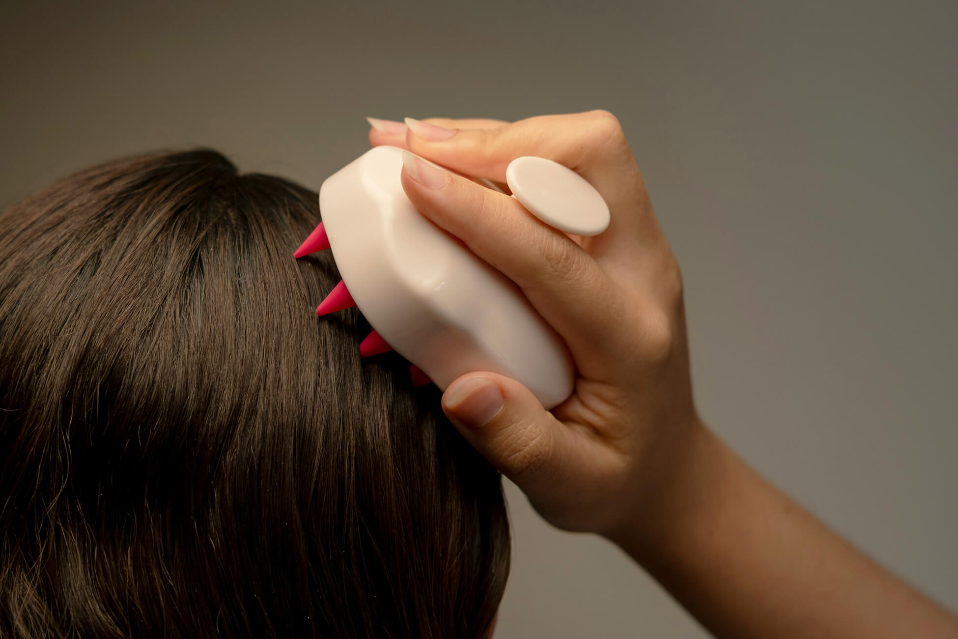 Person using a handheld scalp massage tool to stimulate circulation and support hair growth at home.