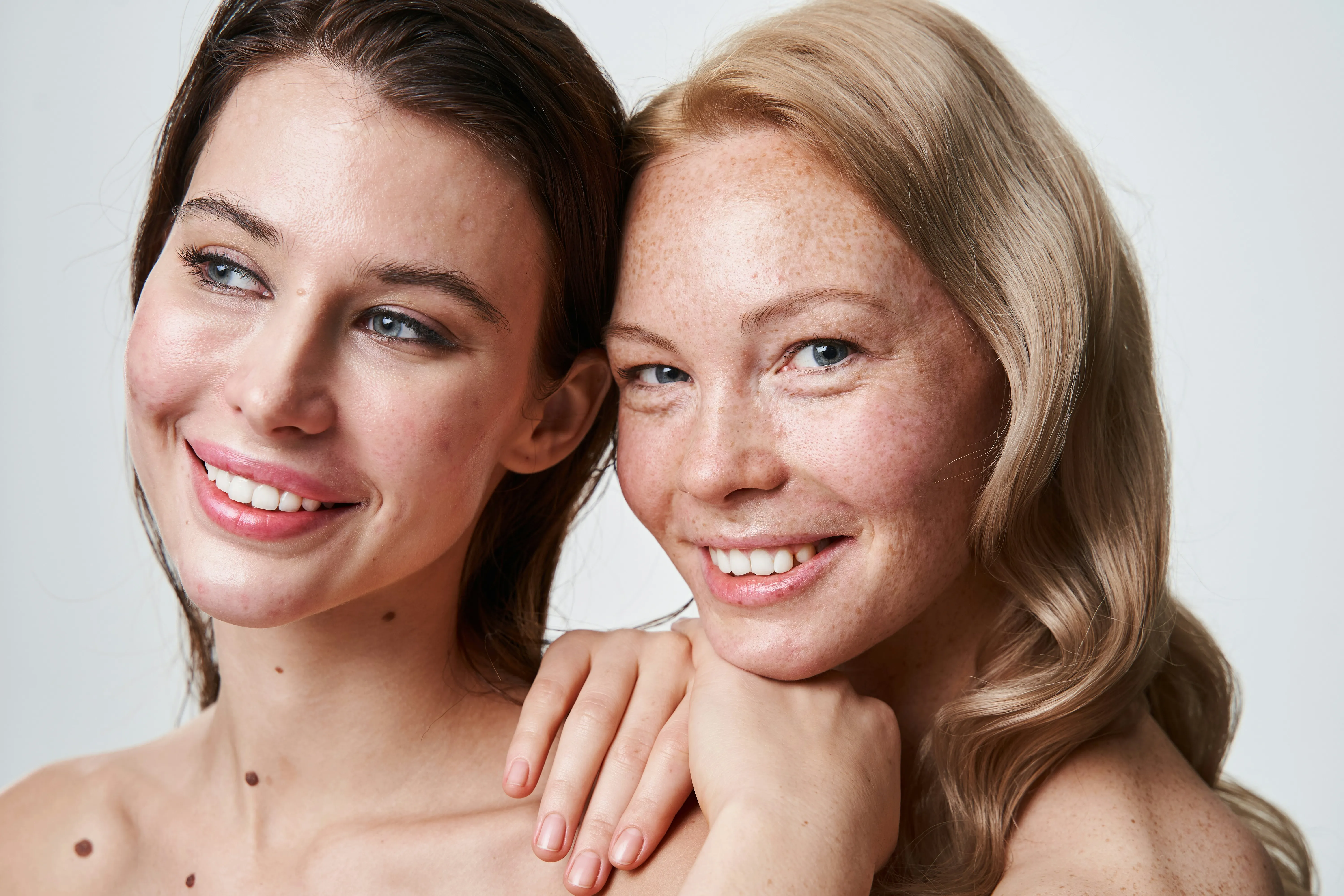 Two women with healthy, glowing skin representing the smoother complexion that may be achieved after a series of microneedling treatments