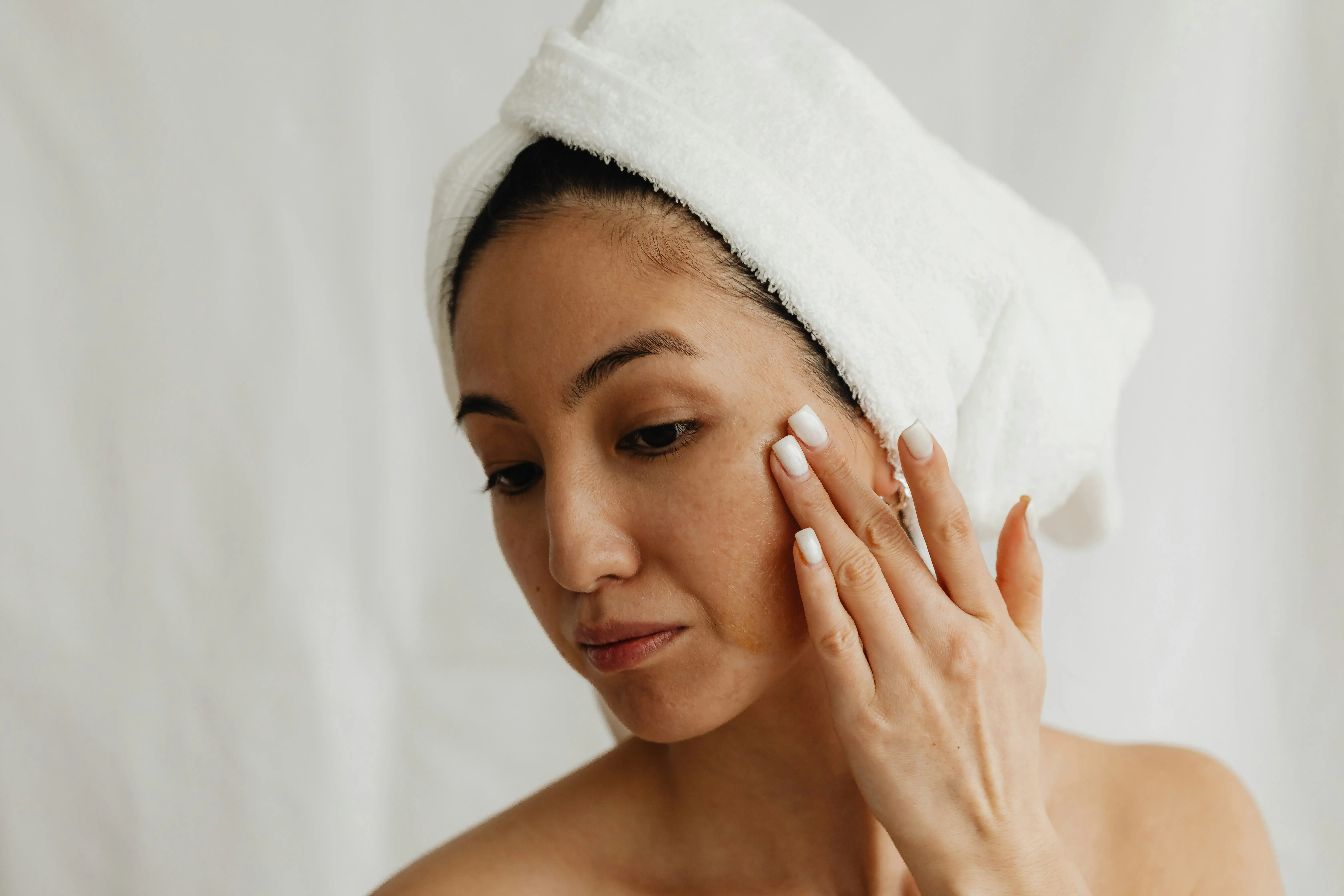 Woman with uneven skin tone applying skincare to support healthy skin after an IPL photofacial treatment