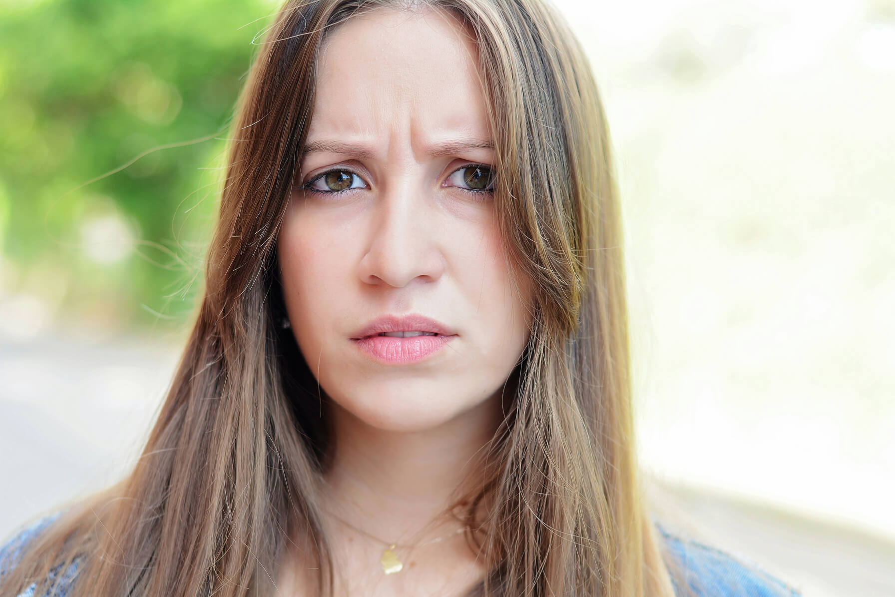 Young woman frowning, showing how repeated facial expressions contribute to the formation of fine lines over time.