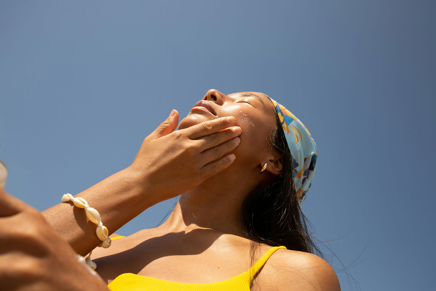 Woman applying sunscreen outdoors to help protect against UV damage, one of the leading causes of premature fine lines.