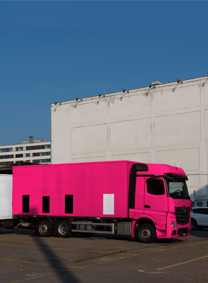 Mockup from Maison Mockup - Bright pink semi-truck parked in an urban lot with a white building backdrop under clear sky.