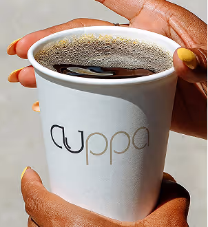 AI Generated image with ChatGpt - Hands with yellow nail polish holding a white cup of black coffee with cuppa logo.