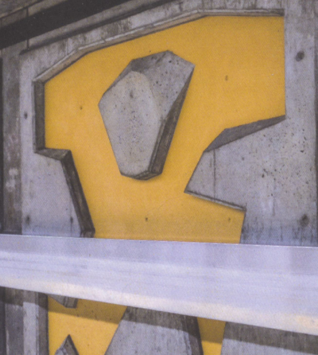 Yellow stylized letter 'K' mounted on a metal surface behind a white barrier.