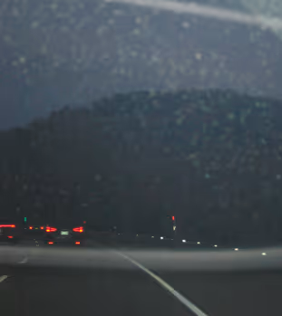 Night highway scene with car taillights and dark hills in the background.