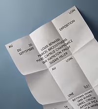 Folded white paper with black text listing artists and exhibition details on a blue background.