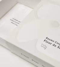 A white rectangular box with French text and a semi-transparent glove resting on top.