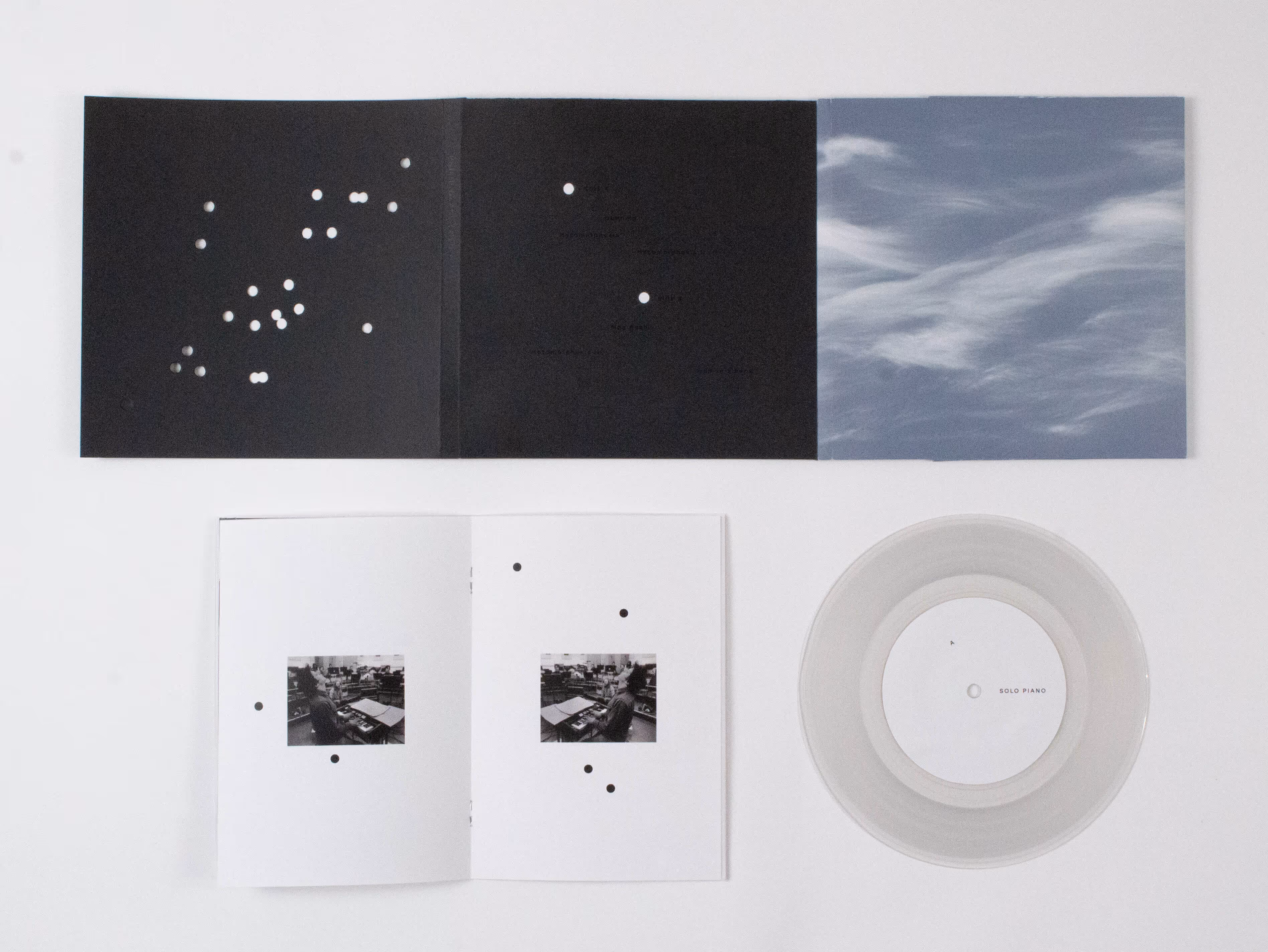 Clear vinyl record labeled Solo Piano with black-and-white booklets and a cloudy sky-themed cover.