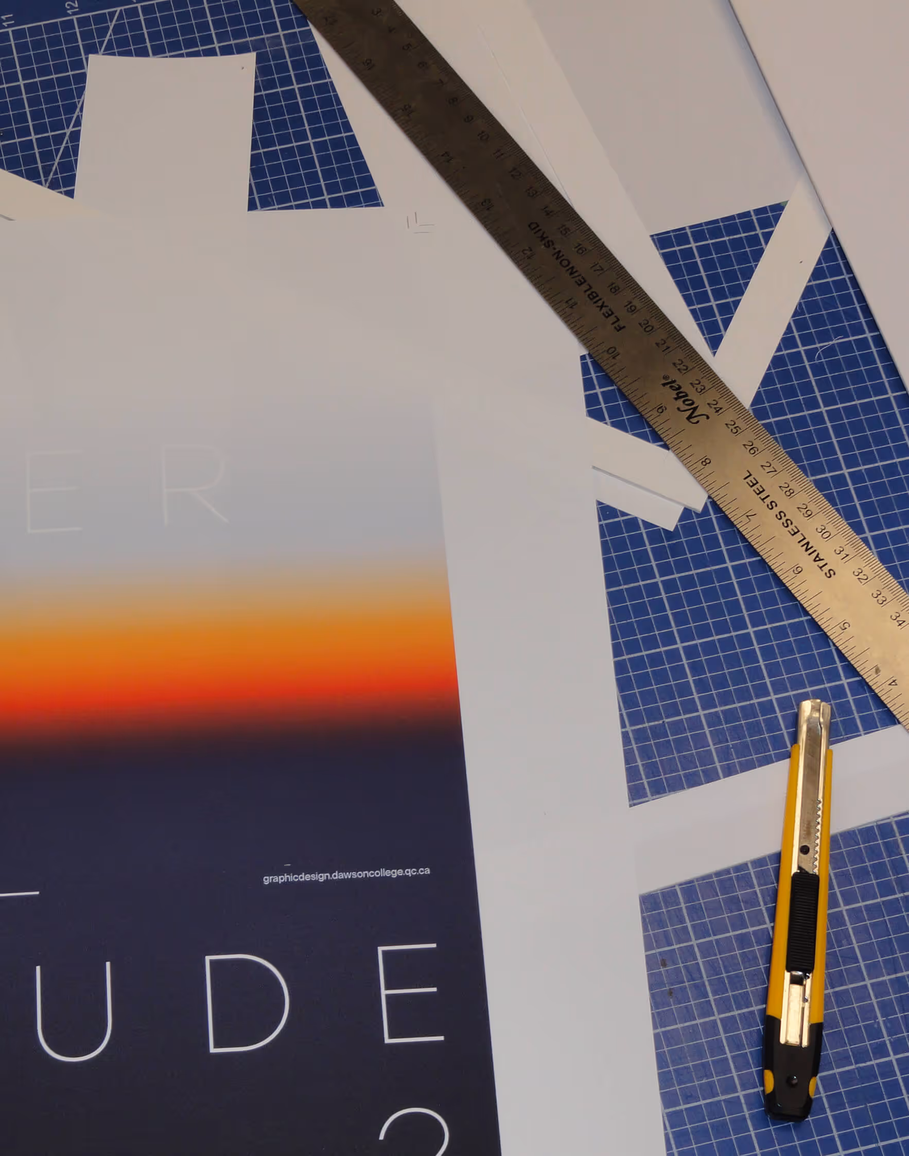 Cutting mat with a gradient poster, stainless steel ruler, and yellow utility knife.