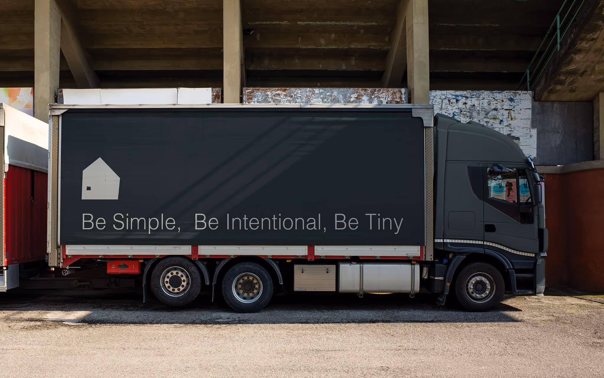Side view of a truck with a dark trailer displaying the text: Be Simple, Be Intentional, Be Tiny.