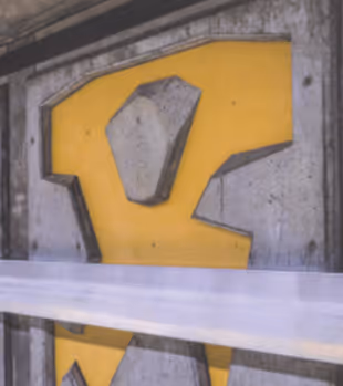 Close-up of a construction barrier with a yellow panel and concrete block behind white tape.
