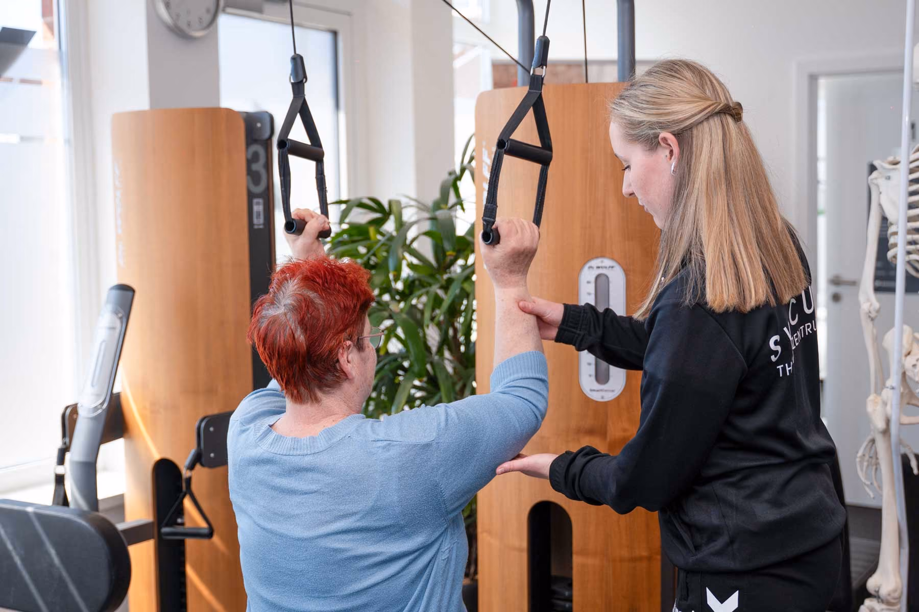 Physiotherapie Team arbeitet gemeinsam im hellen Behandlungsraum bei Planung und Austausch in professioneller Praxisumgebung