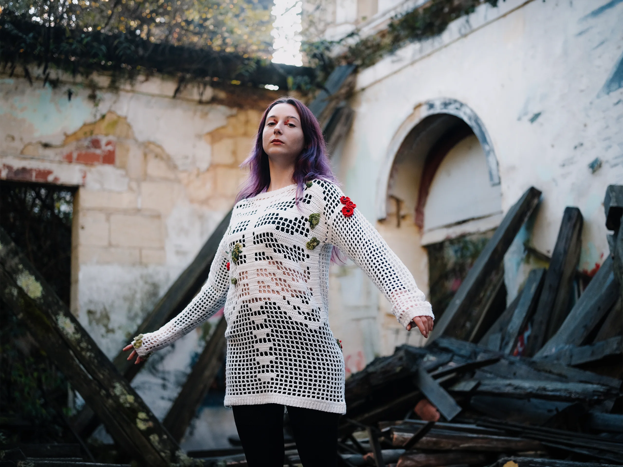 Pull Terra Resumit en crochet d'art blanc, coquelicots brodés en relief, porté dans une ruine végétalisée