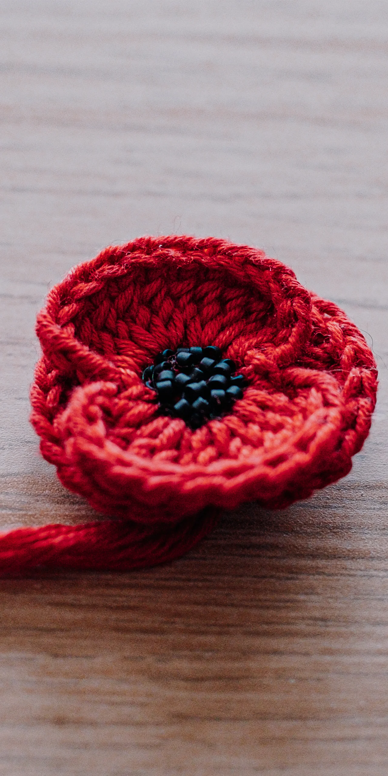 Coquelicot en crochet rouge au cœur de perles noires cousues main, détail du pull Terra Resumit