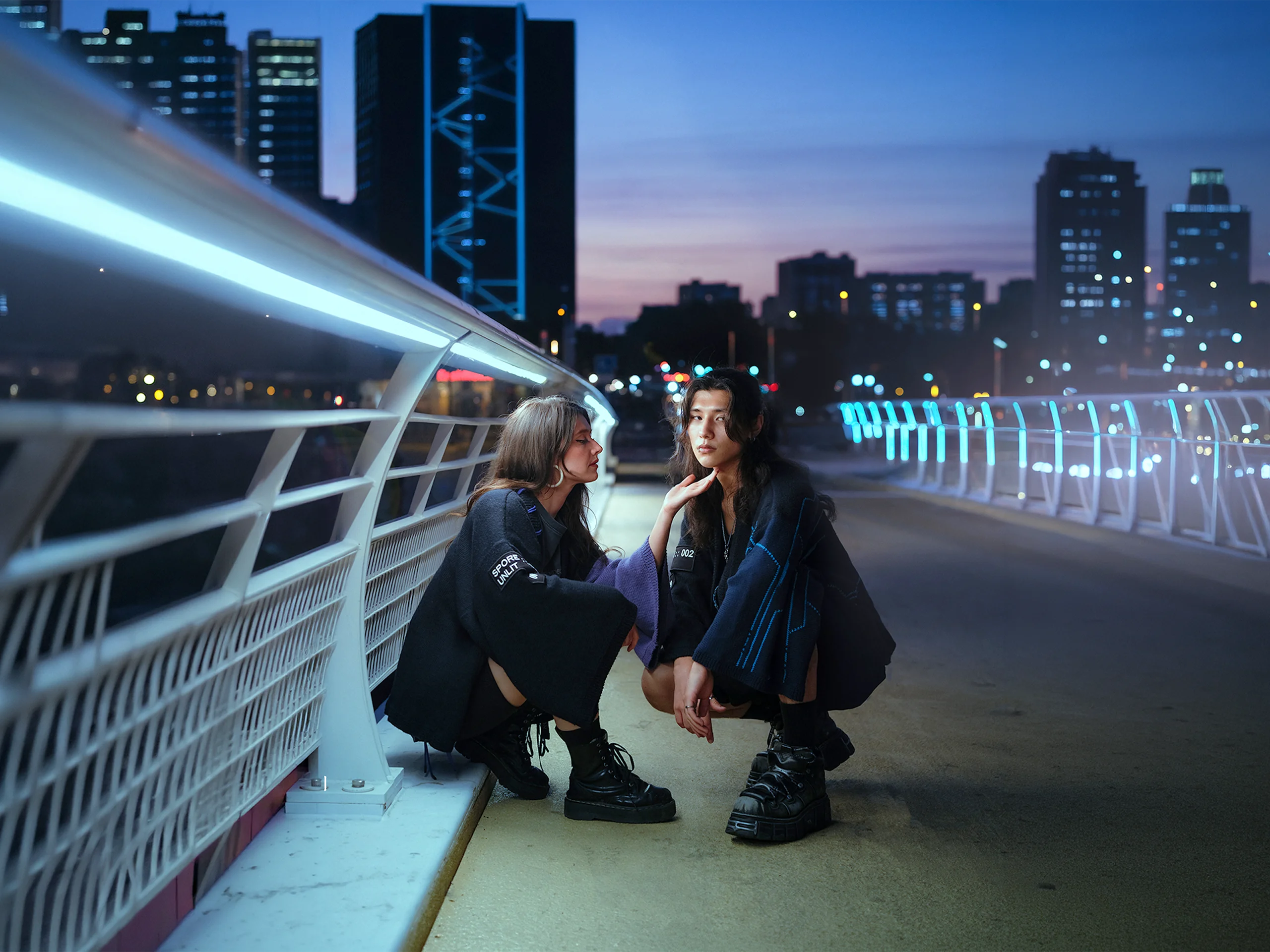 Deux personnes en kimonos Nox face à face sur une passerelle éclairée au crépuscule, tricot artisanal Procyon