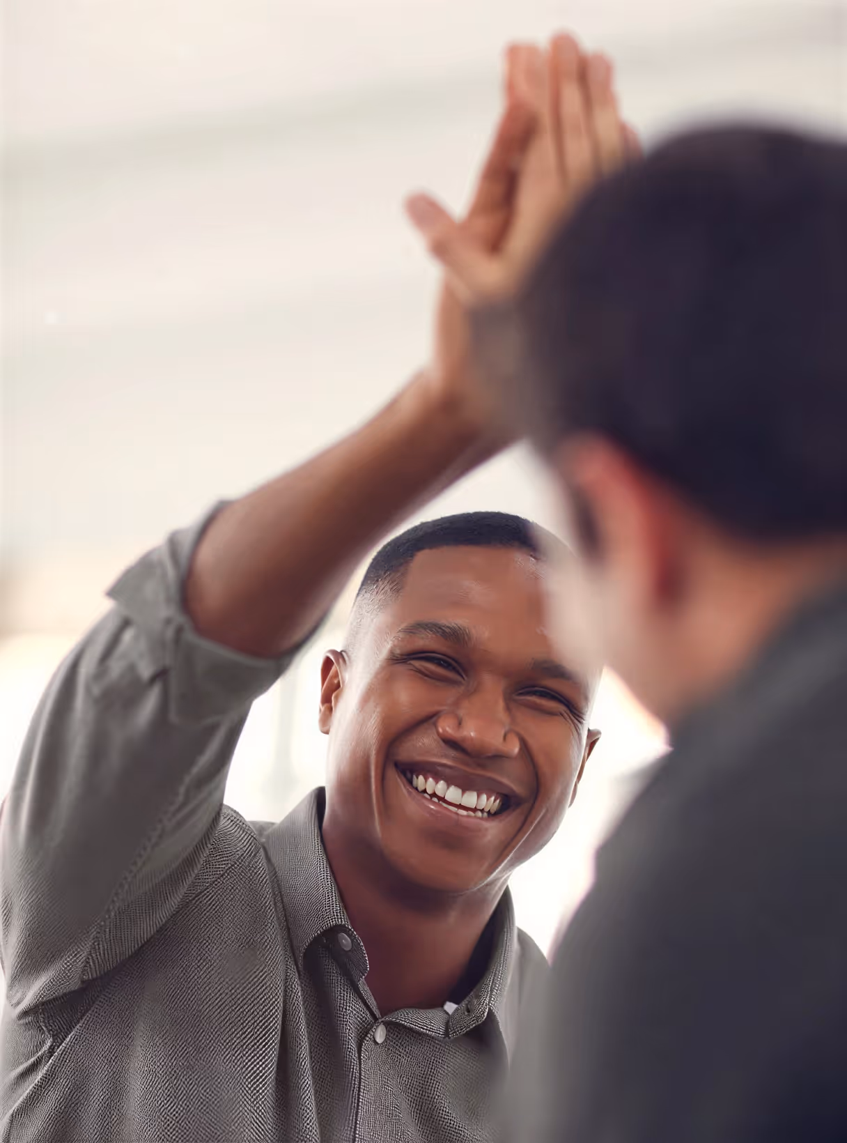 Smiling man giving a high five to another person.