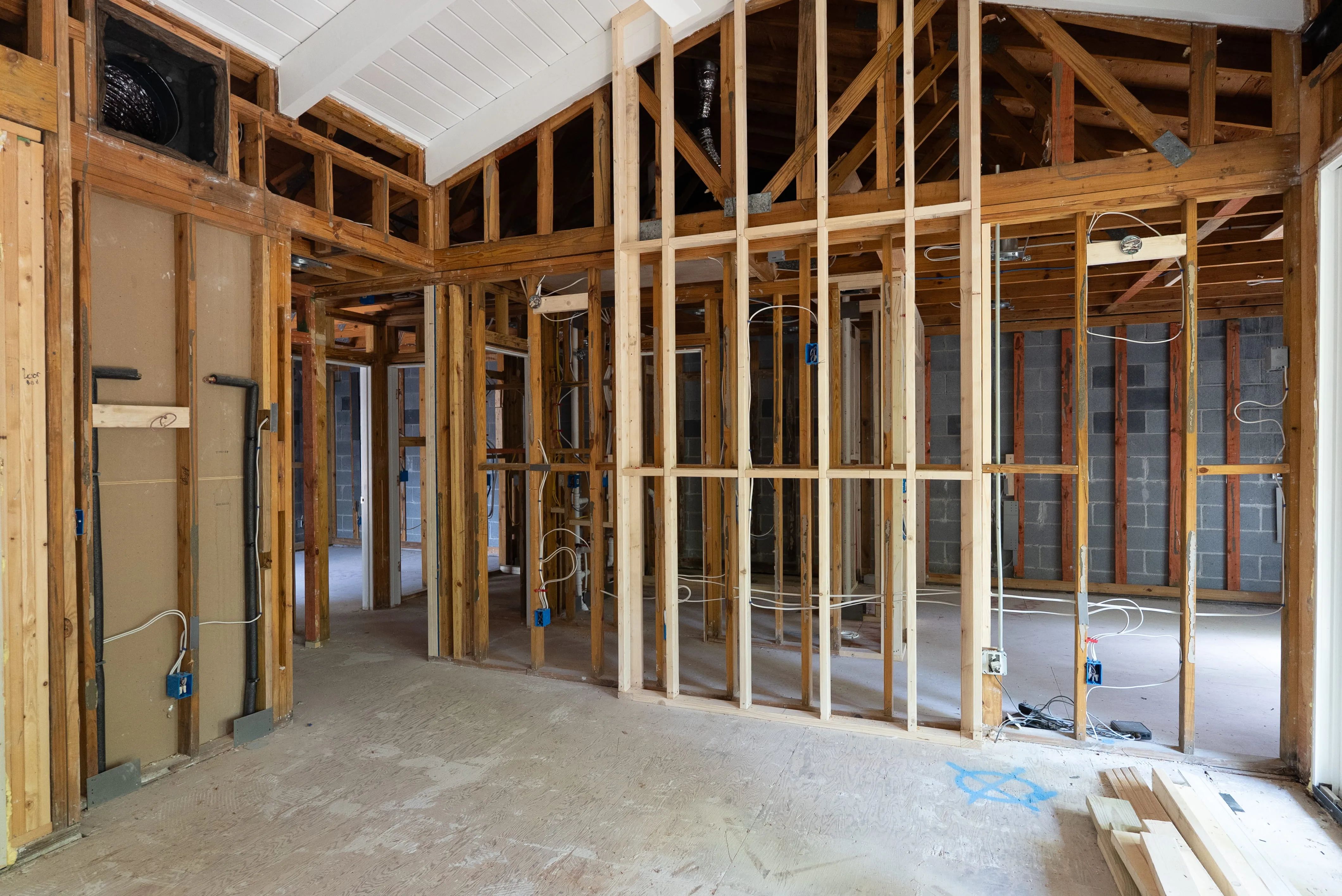 Interior of a house under construction showing exposed wooden framing and electrical wiring.