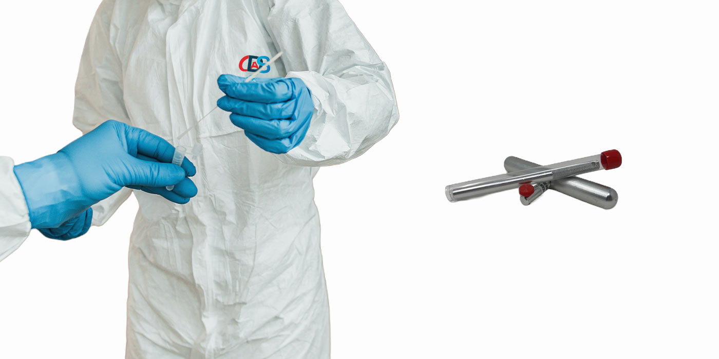 Person in white protective gear and blue gloves holding a swab and test tube with two metal sample tubes nearby.