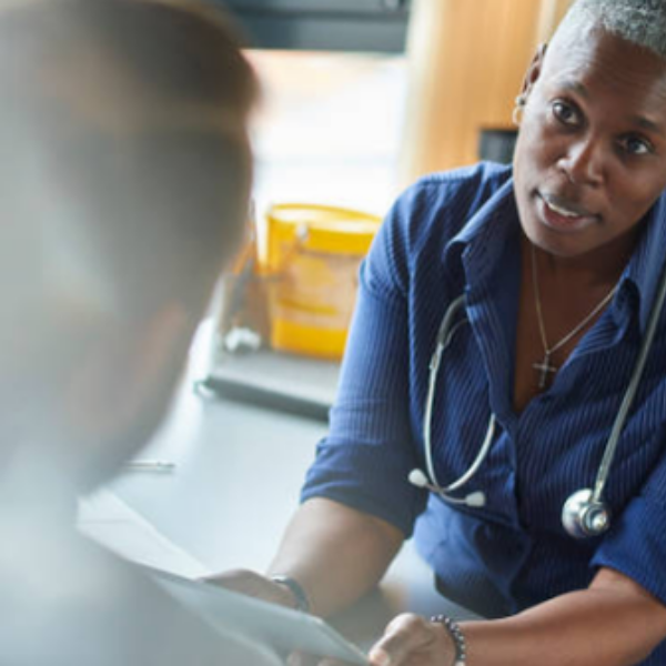 Medical professional with stethoscope consulting a patient in a clinical setting.