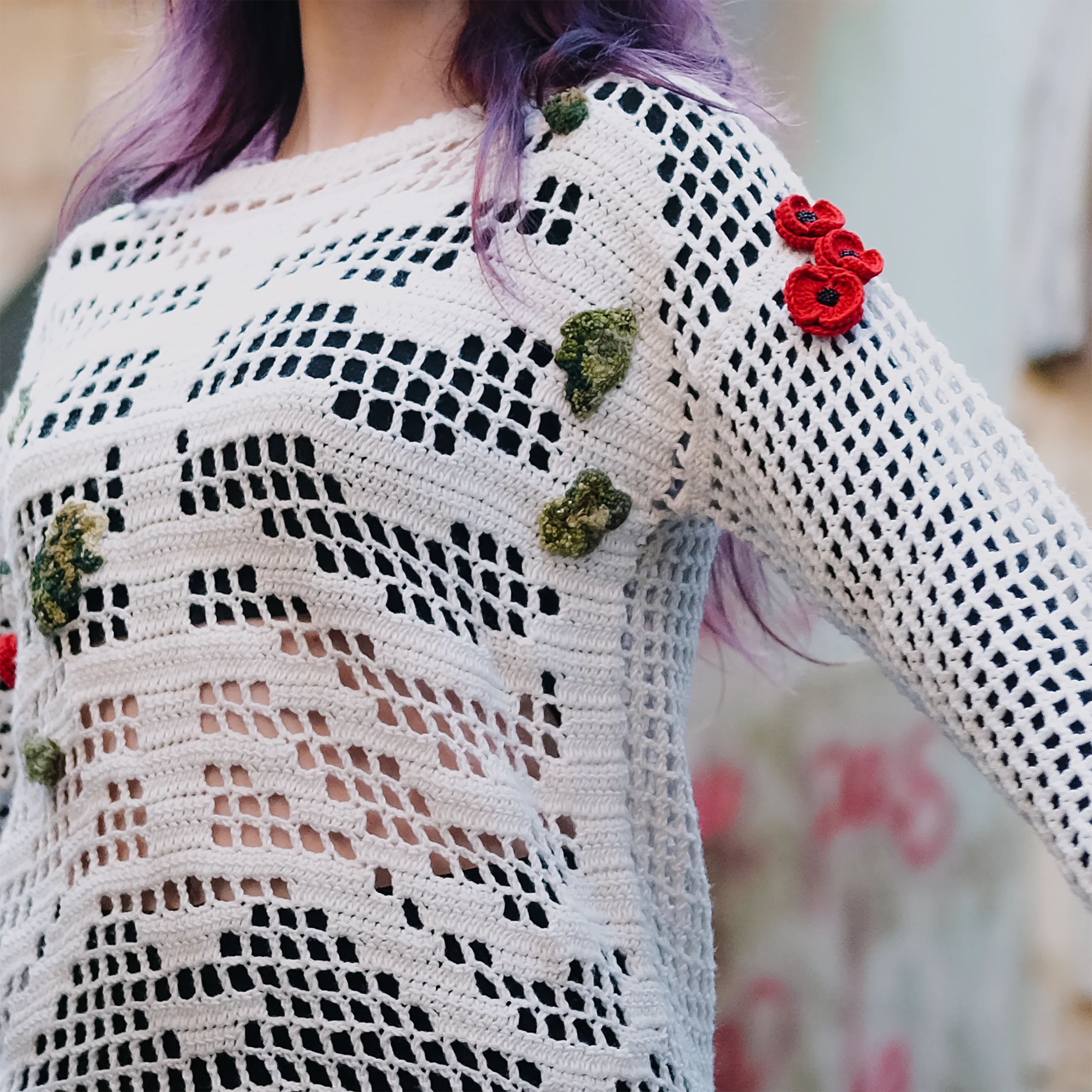 Épaule du pull Terra Resumit : trois coquelicots crochetés et mousses vertes en relief sur le filet