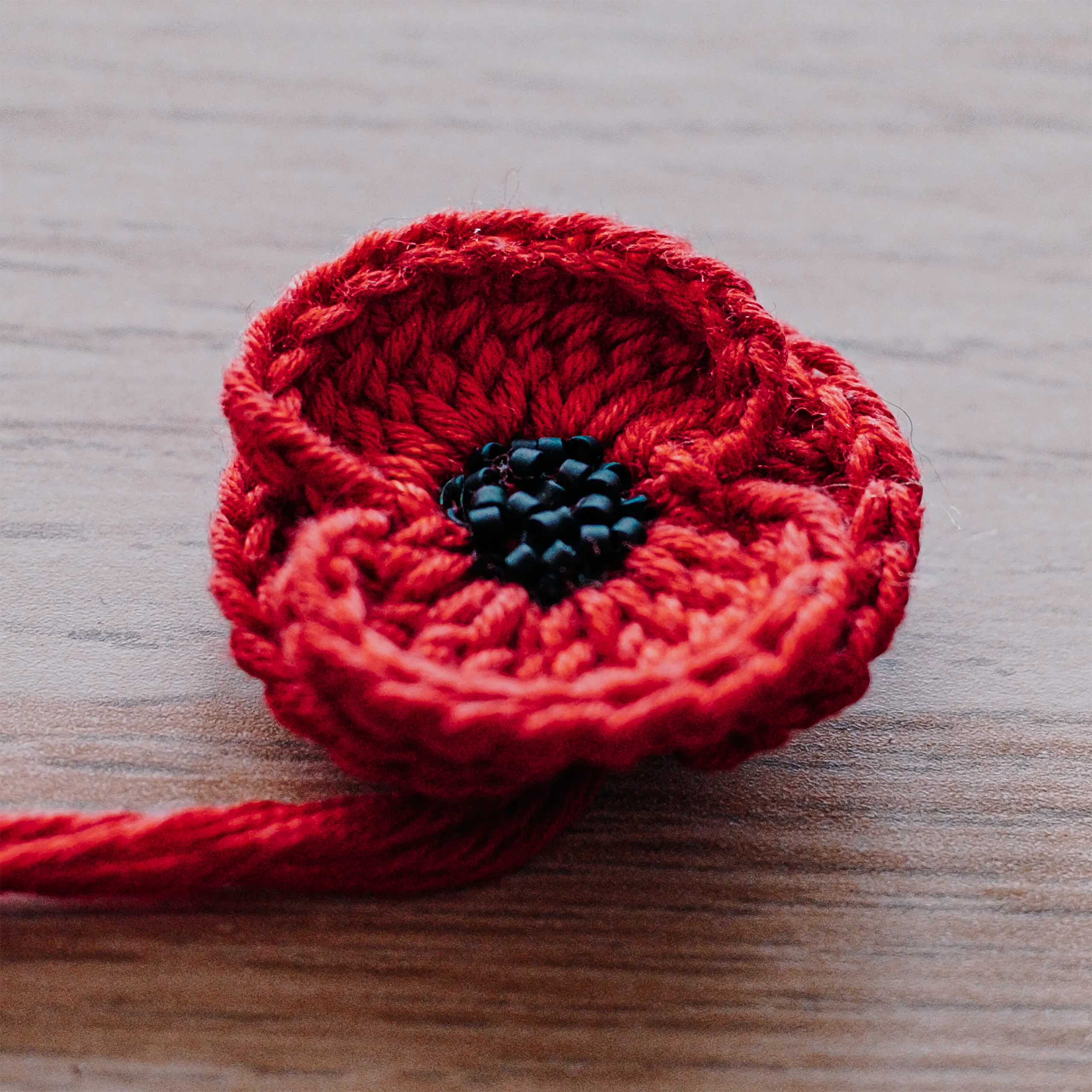 Coquelicot en crochet du pull Terra Resumit, cœur de perles Miyuki noires cousues une à une