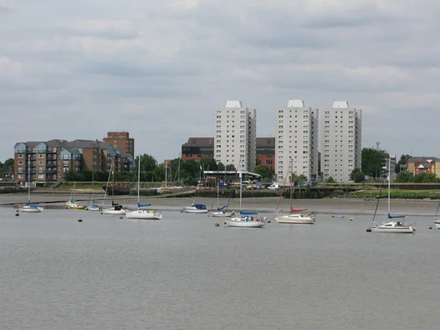 Boats moored on the Thames with flats and tower blocks along the Grays riverside