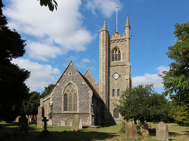 Flint and stone tower of St Margaret of Antioch Church, Stanford-le-Hope, above the churchyard