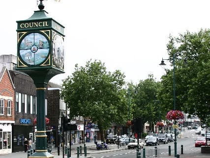 Green and gold clock on Rayleigh High Street with shops behind