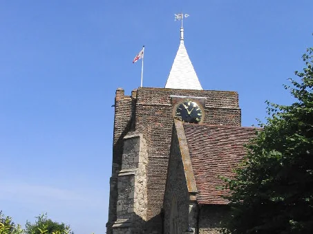 Clock tower and white spire of Orsett parish church against a blue sky