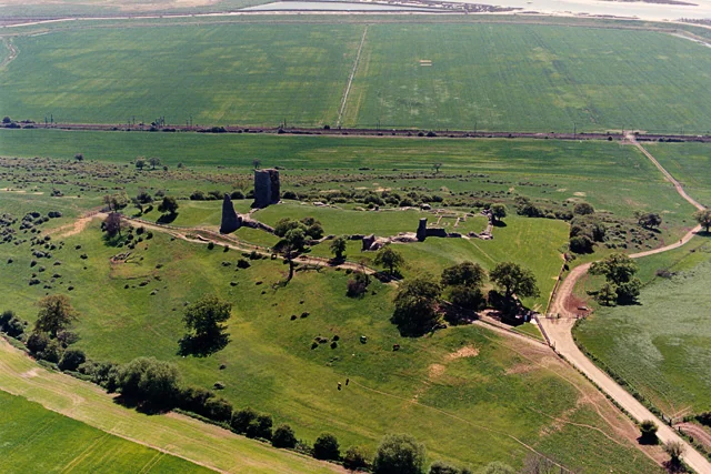 Aerial view of Hadleigh Castle ruins on the green slope above the Thames Estuary marshes