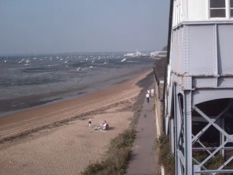 Seafront path and beach at Chalkwell beside the station footbridge, with boats moored offshore