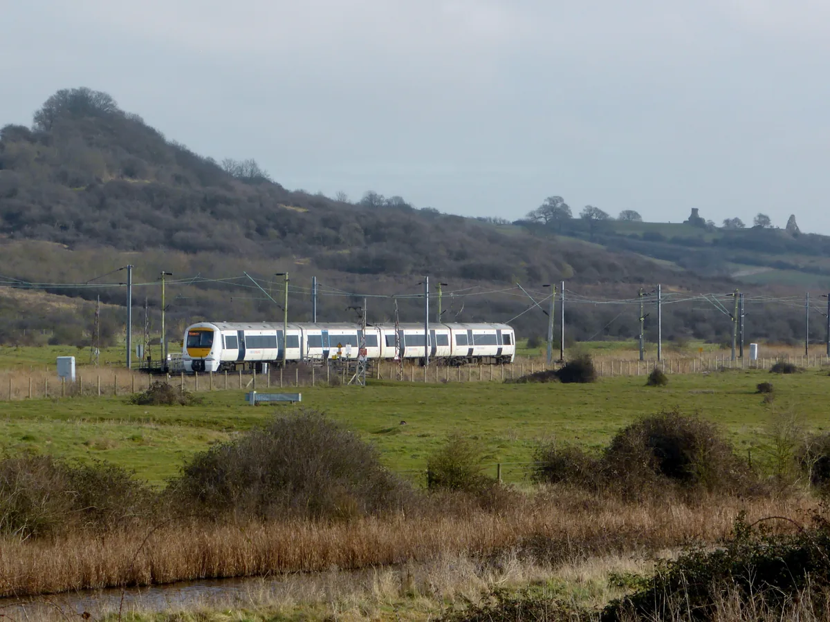 c2c train crossing the marshes below Hadleigh Downs, with the castle ruins on the ridge