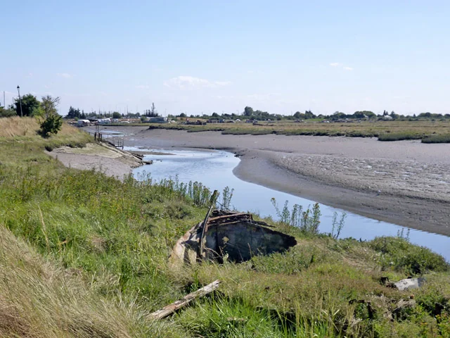 Benfleet Creek at low tide with an old boat wreck in the grass on the bank