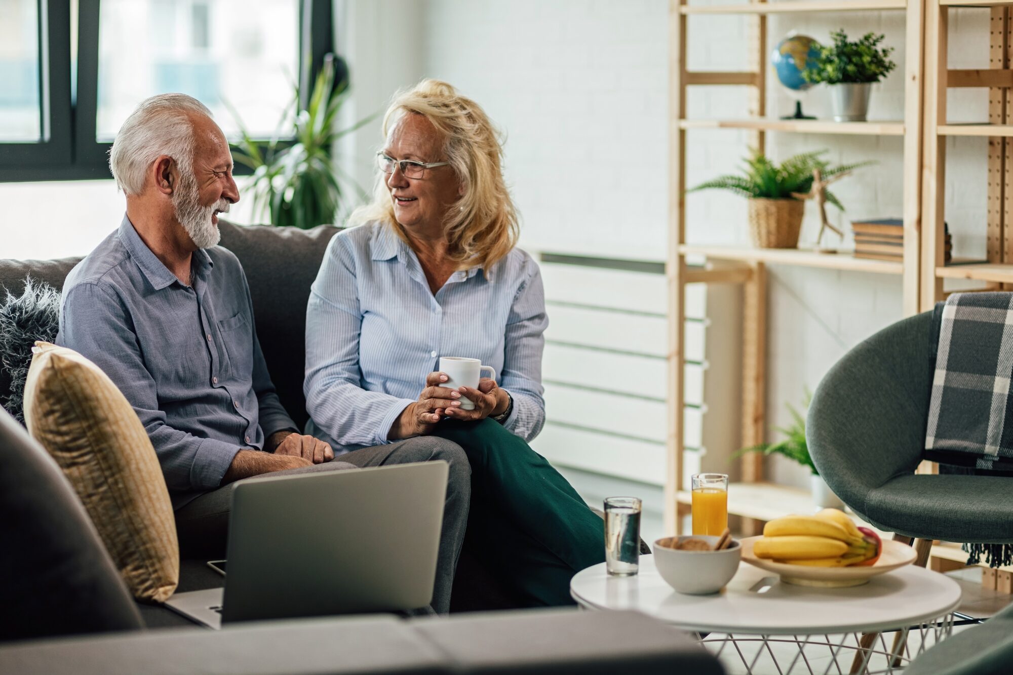 Older couple talking over coffee on the sofa at home