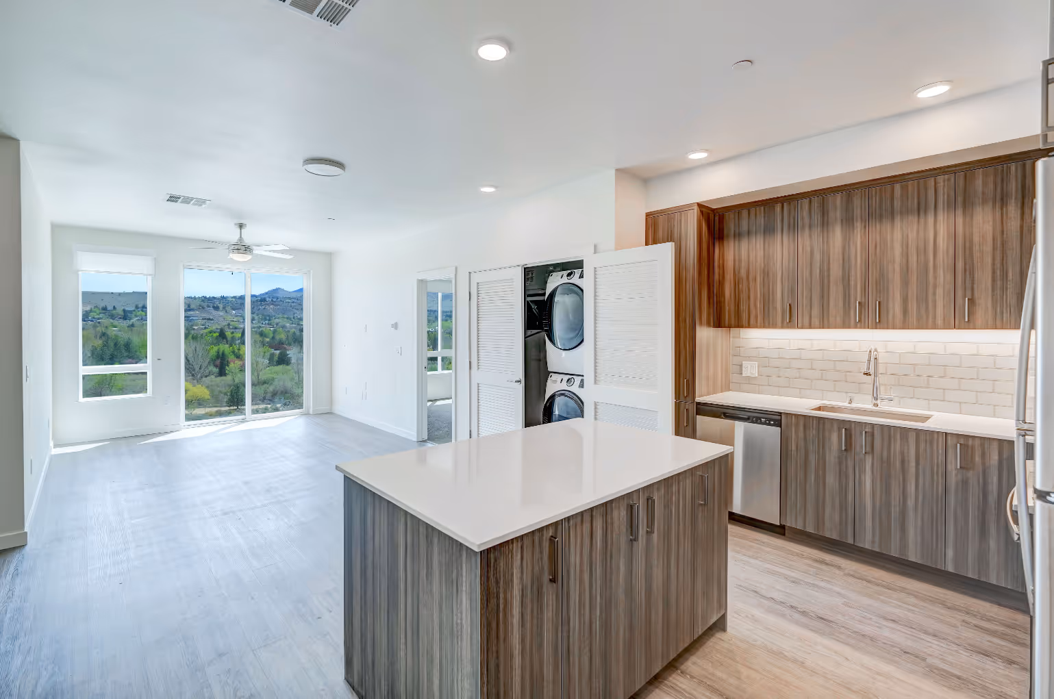 Wide view of kitchen with island and view of laundry room with stacked appliances
