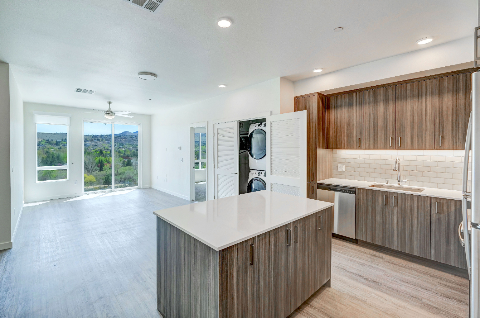 Wide view of kitchen with island and view of laundry room with stacked appliances