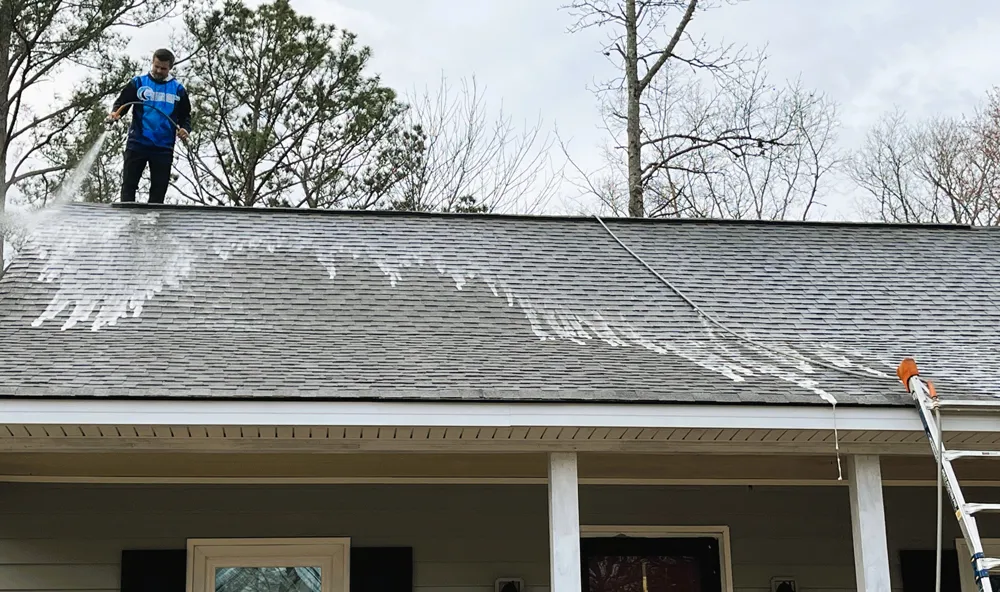 Technician performing gutter cleaning to ensure proper drainage for a residential property.