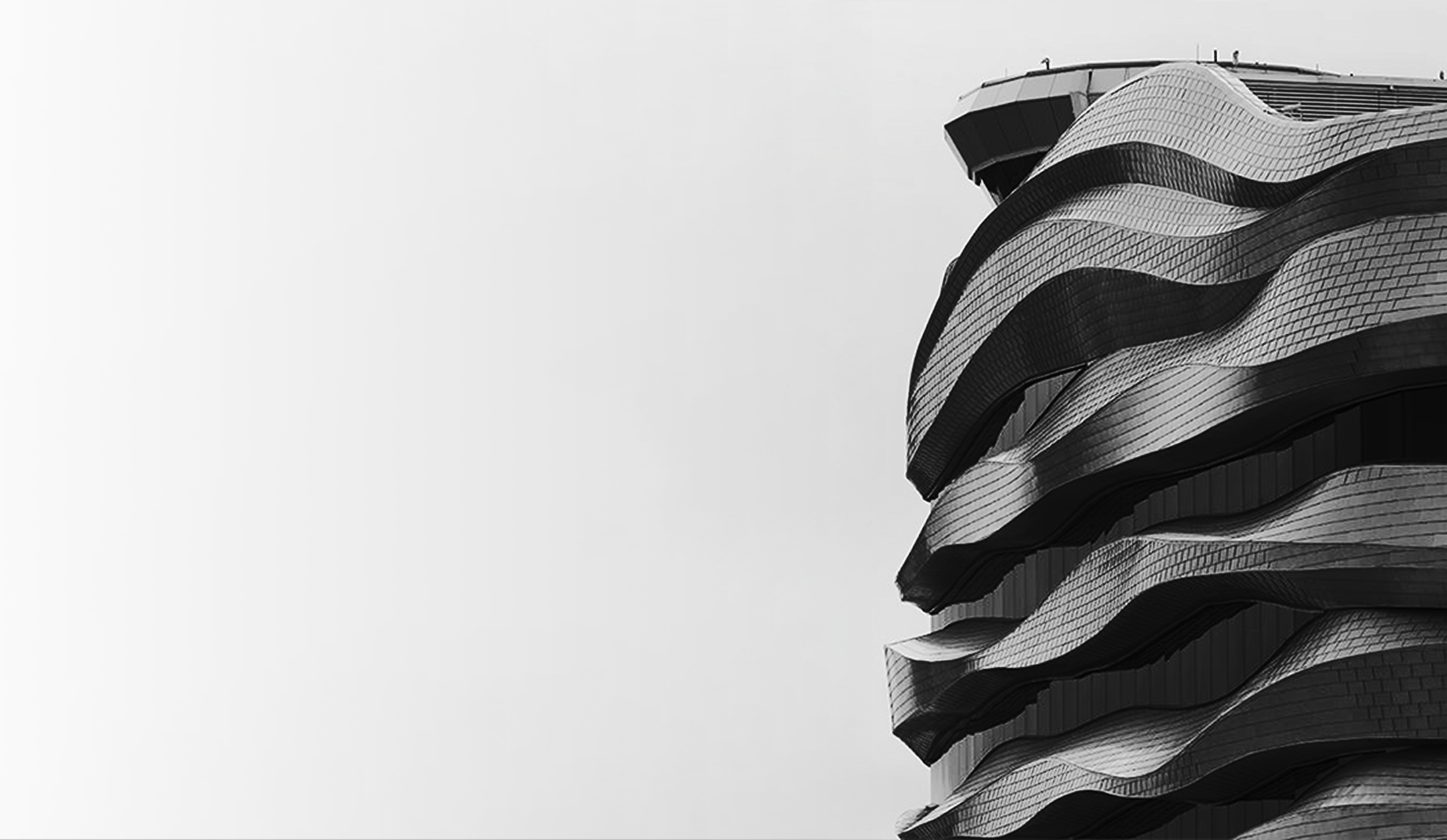 Section of modern building with undulating curved metal facade in black and white.