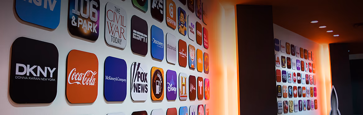 Wall display of various company and media logos arranged in a grid pattern with warm lighting.
