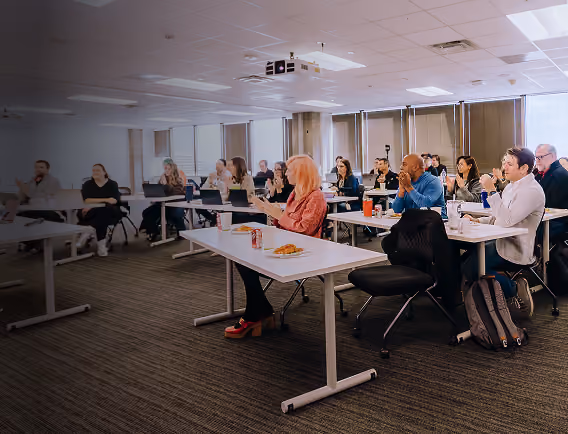 People seated in a classroom applauding during a presentation or lecture.