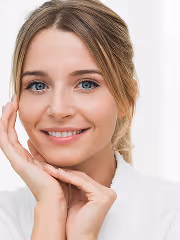 Smiling woman with blue eyes and blonde hair resting her face on her hands.