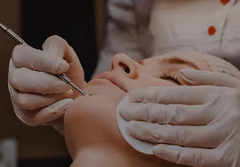 Close-up of a person receiving a facial skin treatment for acne with a gloved professional using a metal extraction tool.